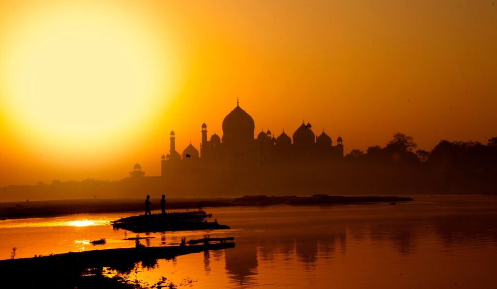 Taj Mahal sunset reflection in Yamuna River with golden hour light