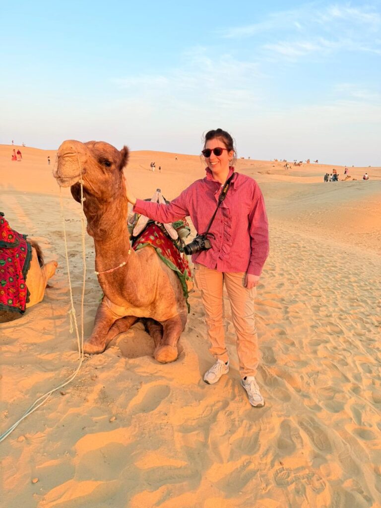 Female traveler enjoying a camel safari in the Jaisalmer Desert, Rajasthan during a luxury Rajasthan tour