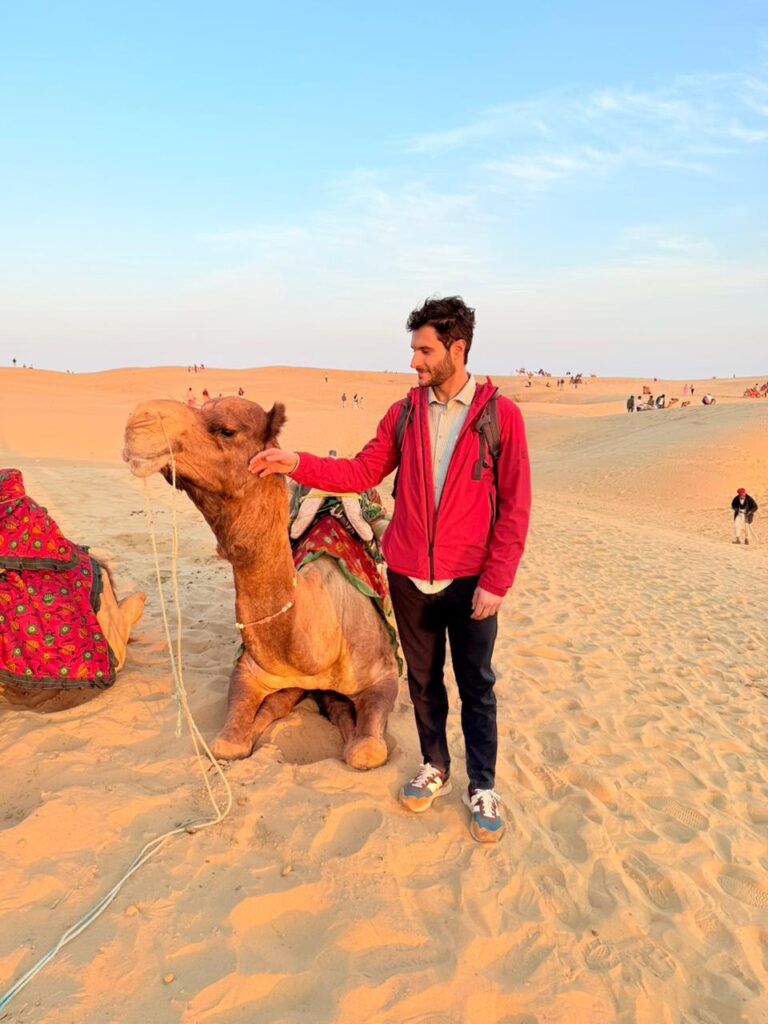 Traveler with camel during sunset camel safari in the Thar Desert, Jaisalmer, Rajasthan, India